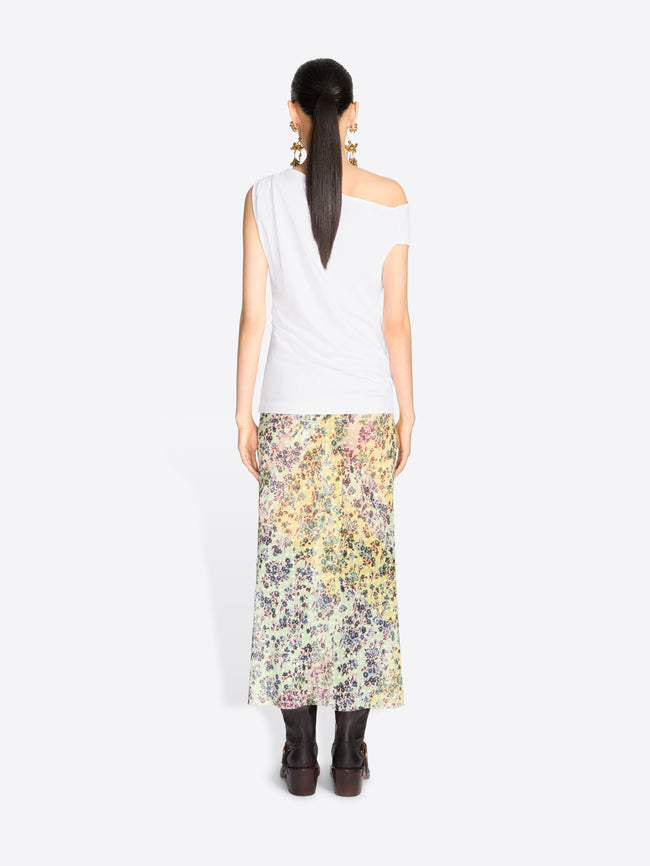 Back view of a model standing against a light gray background wearing a white asymmetrical off-the-shoulder top and a long floral print midi skirt.