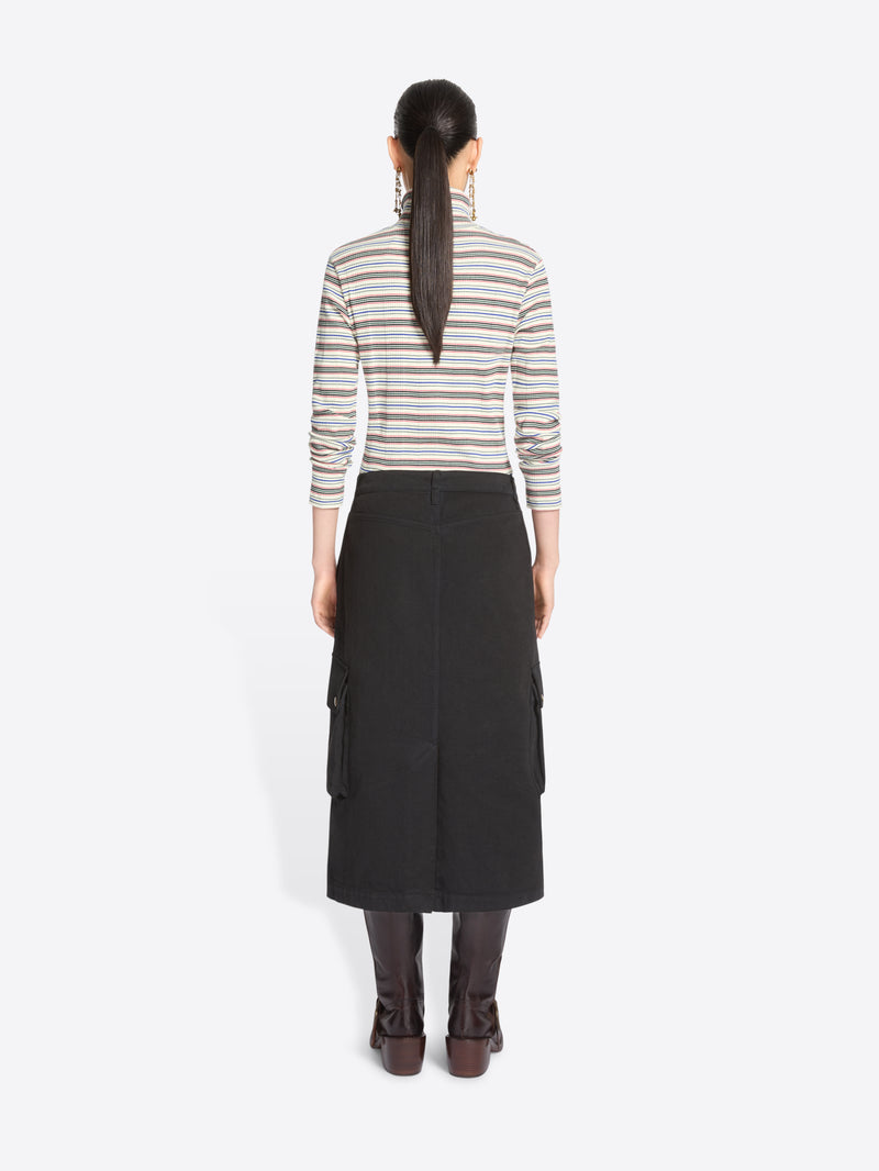 Back view of a model standing against a light gray background wearing a striped turtleneck sweater, a black cargo midi skirt with front flap pocket and dark brown knee-high boots.
