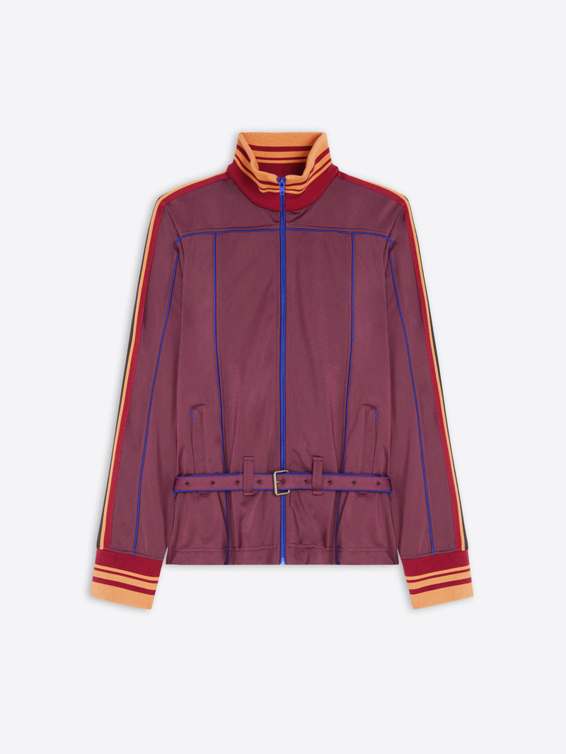 A women's zip-up track jacket in a muted burgundy-purple color, featuring blue piping details, orange and yellow striped accents on the collar, cuffs, and sleeves, and a matching purple belt with a silver buckle.