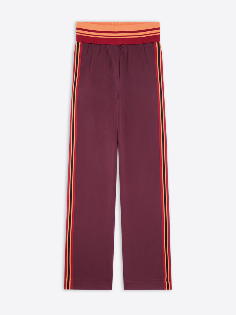 A pair of wide-leg pants in maroon, featuring double vertical stripes in yellow and orange running down the sides, with a matching red and orange striped elastic waistband.