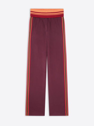 A pair of wide-leg pants in maroon, featuring double vertical stripes in yellow and orange running down the sides, with a matching red and orange striped elastic waistband.
