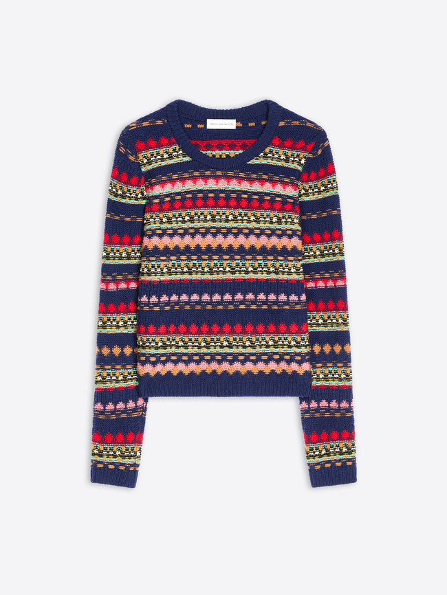 A cropped long-sleeve knit sweater with a multicolor pattern on a navy blue base, displayed flat against a light gray background.