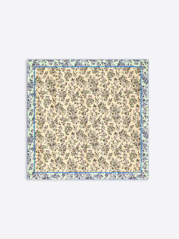 A square scarf with a dense floral print, featuring a cream center and a wider outer border in muted green and blue tones, shown flat against a light gray background.