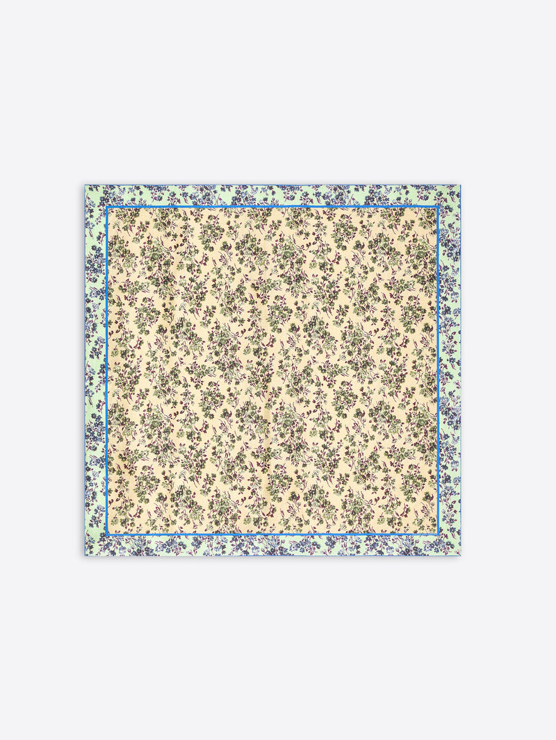 A square scarf with a dense floral print, featuring a cream center and a wider outer border in muted green and blue tones, shown flat against a light gray background.