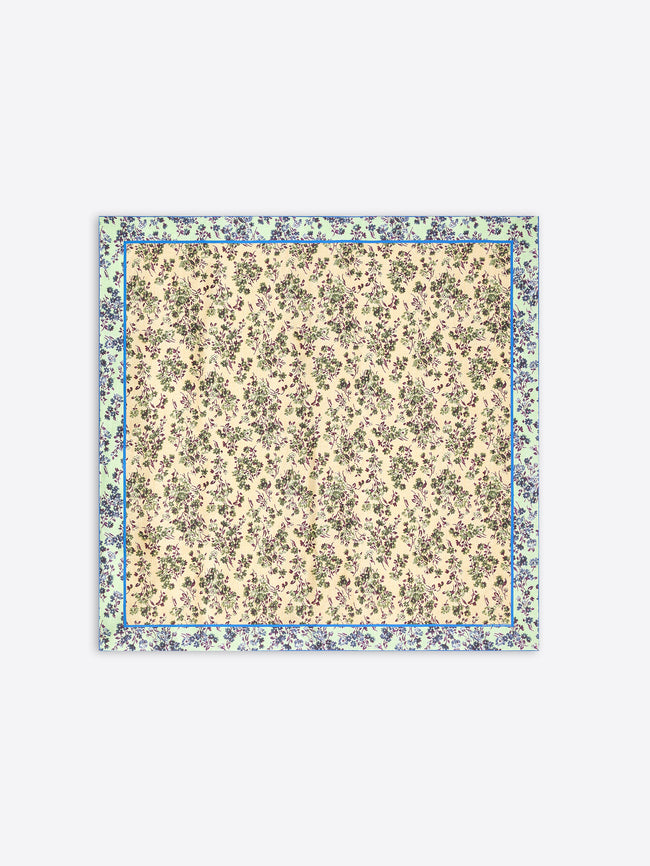 A square scarf with a dense floral print, featuring a cream center and a wider outer border in muted green and blue tones, shown flat against a light gray background.