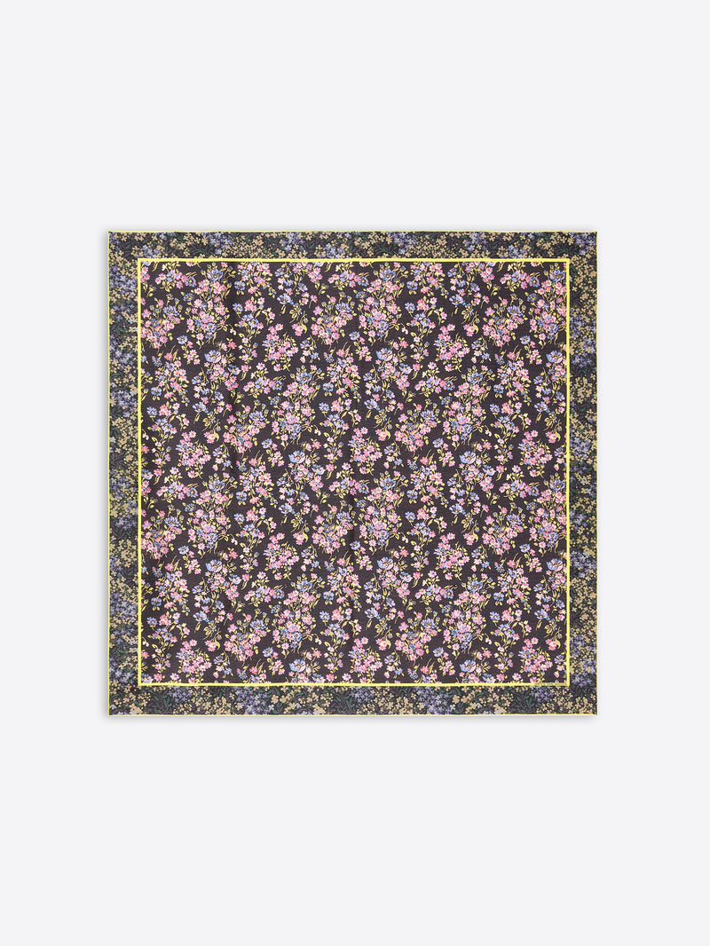A square scarf featuring an all-over dense floral print  on a dark background, framed by a thin yellow border on a light gray background.