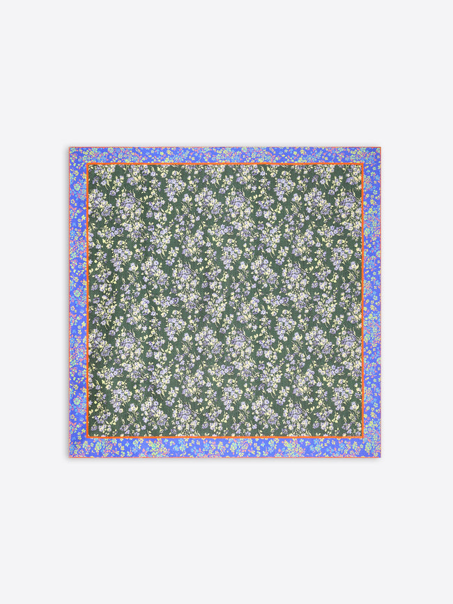 A square scarf featuring a dark green background with a dense white and light blue floral pattern, framed by a lilac border with small yellow accents on a light gray background.