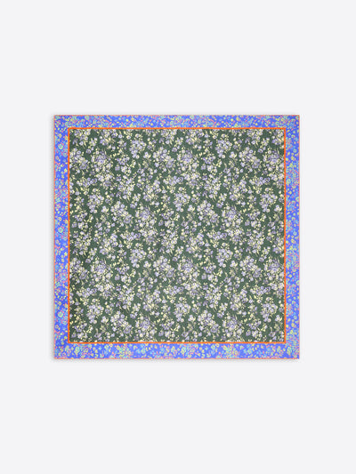 A square scarf featuring a dark green background with a dense white and light blue floral pattern, framed by a lilac border with small yellow accents on a light gray background.