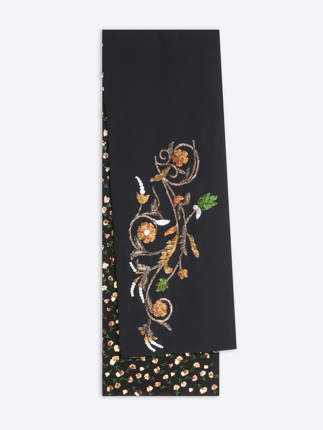 A black top featuring an ornate gold floral vine pattern on one side and a black base with small gold and white floral dots on the reverse, shown against a light gray background.