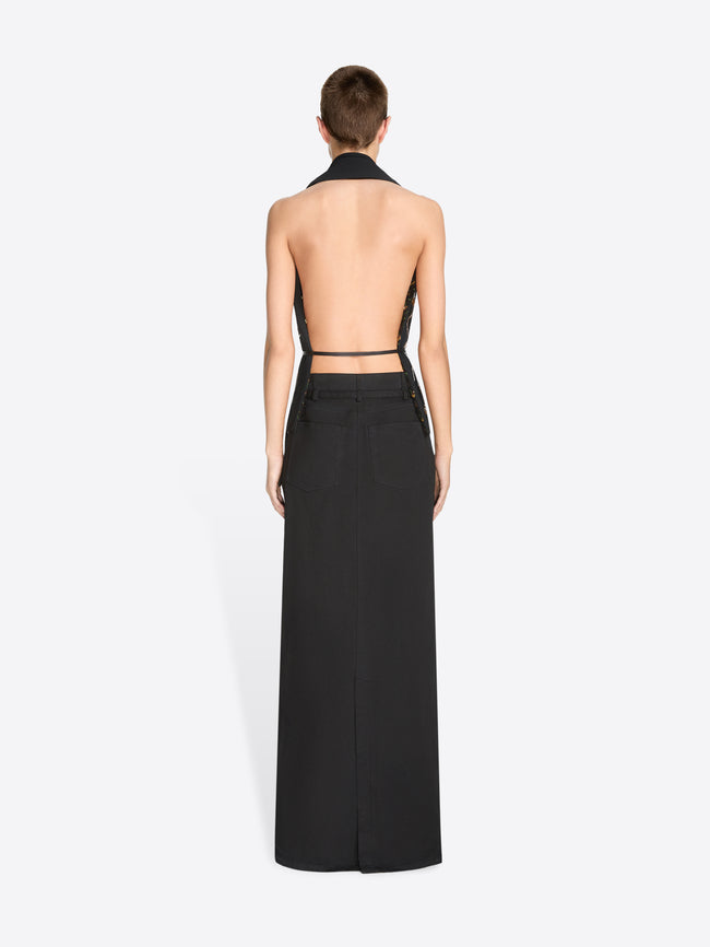 A model wearing a black sleeveless wrap-style top with a low open back paired with a long black skirt against a light gray background.