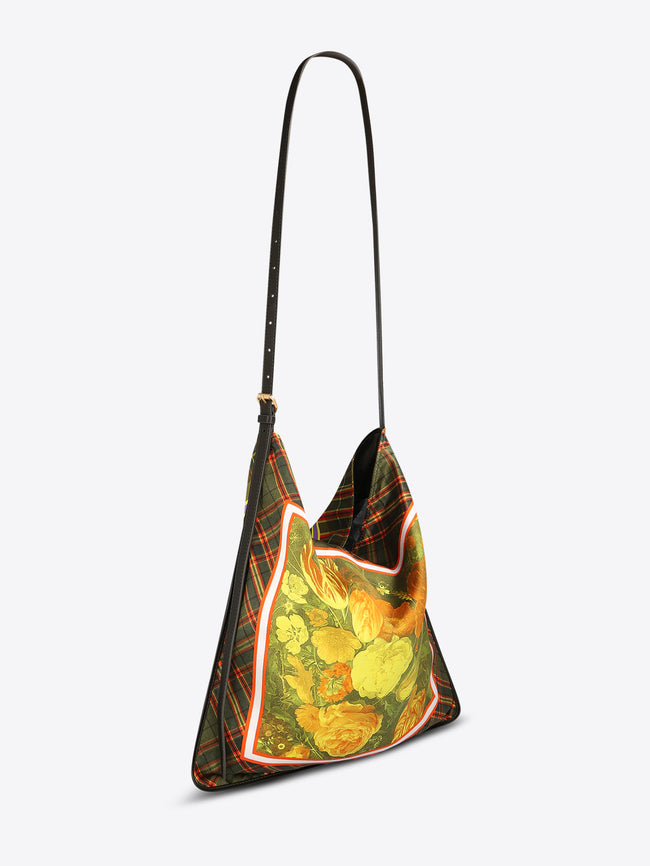 Triangular shoulder bag with a long black strap, green plaid panels, and a yellow-orange floral center framed with red and white trim on a light gray background.
