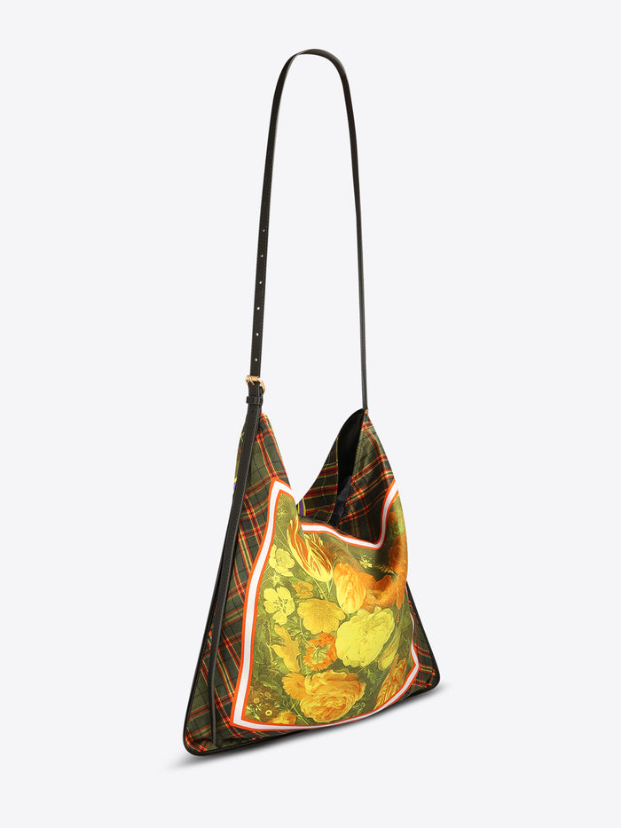 Triangular shoulder bag with a long black strap, green plaid panels, and a yellow-orange floral center framed with red and white trim on a light gray background.
