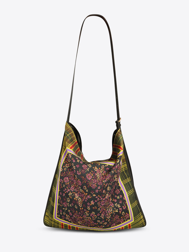 Back view of a triangular shoulder bag with a long black strap, green plaid panels, and a dark floral center framed with yellow and purple trim on a light gray background.