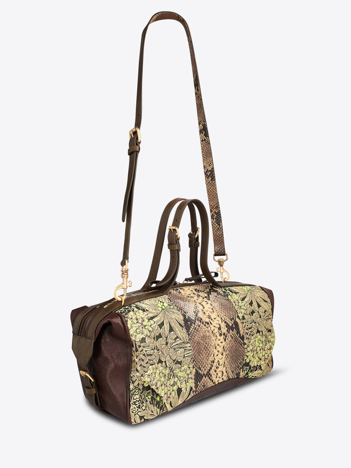 Structured duffle bag with dark brown leather trim, a tan snakeskin-effect center panel, and black-and-gold floral jacquard sides with green accents on a light gray background.