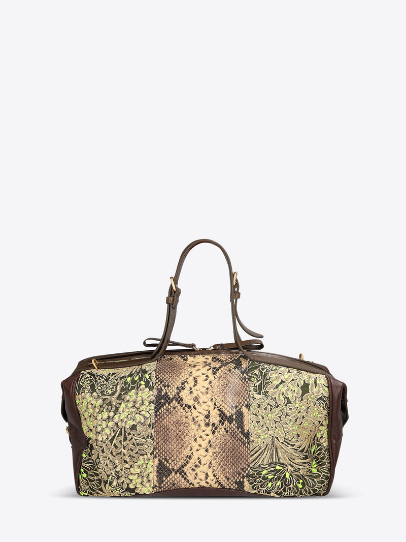 Structured duffle bag with dark brown leather trim, a tan snakeskin-effect center panel, and black-and-gold floral jacquard sides with green accents on a light gray background.