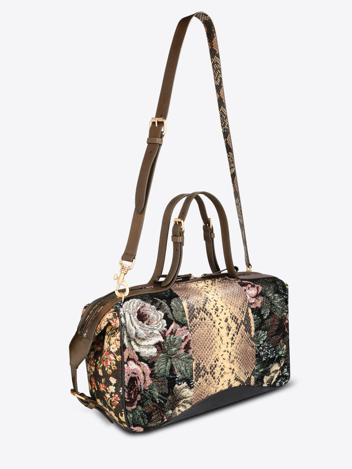 Structured floral jacquard duffle bag with a tan snakeskin-effect center panel, dark brown leather trim, and top handles on a light gray background.