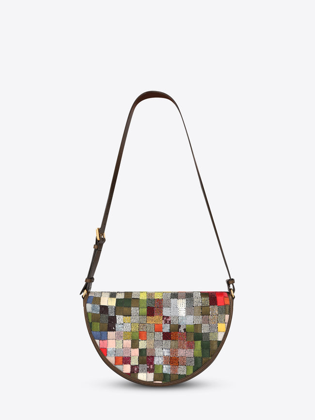 Half-moon shoulder bag with a dark brown leather strap and multicolored textured patchwork panel on a light gray background.