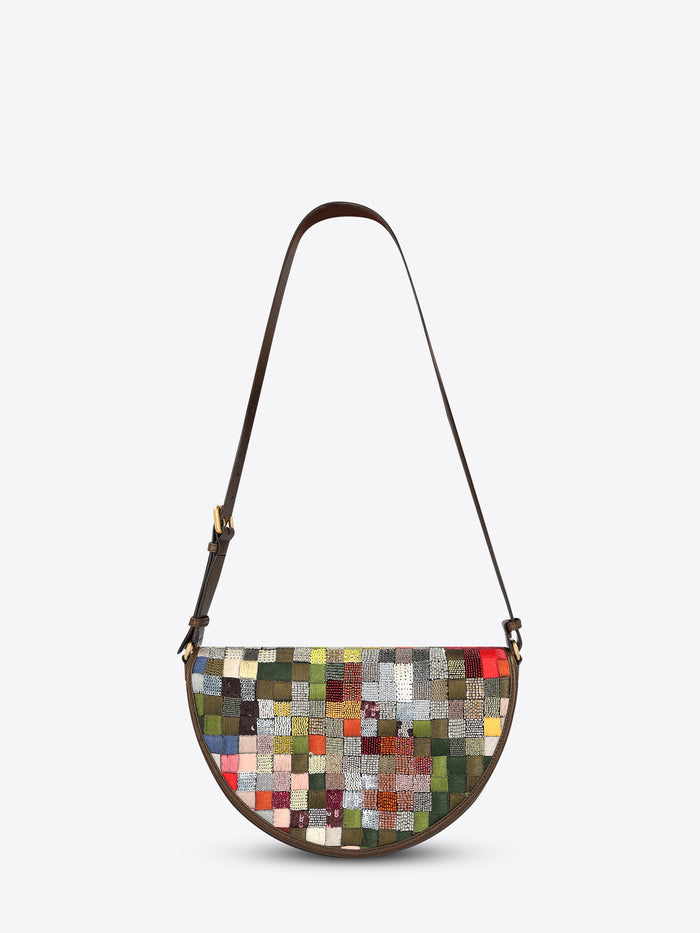 Half-moon shoulder bag with a dark brown leather strap and multicolored textured patchwork panel on a light gray background.