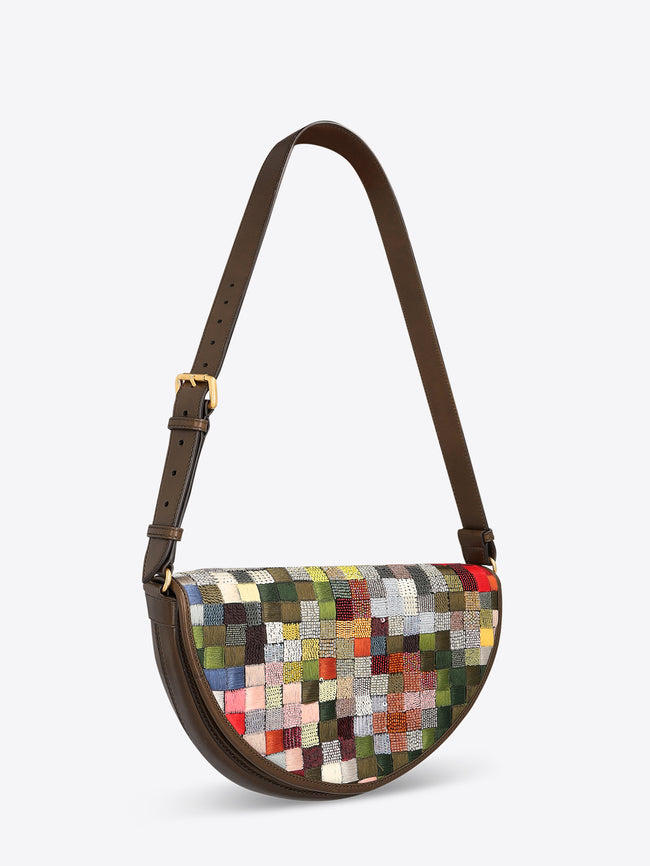 Half-moon shoulder bag with a dark brown leather strap and multicolored textured patchwork panel on a light gray background.