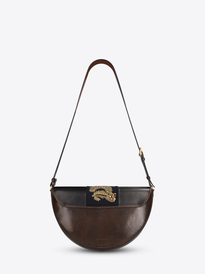 Back view of a leather half-moon shoulder bag with a dark brown strap and a navy center panel featuring ornate gold-toned embroidery and sequins on a light gray background.
