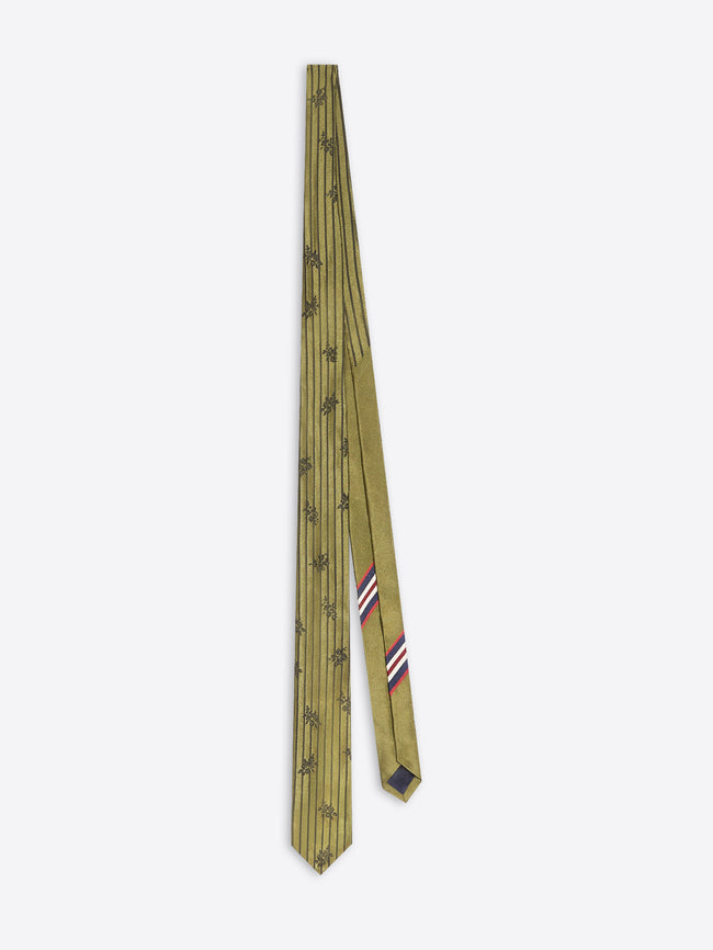 A tie in olive green with a repeating pattern and a small striped accent in red, white, and blue near the tip, displayed on a light gray background.