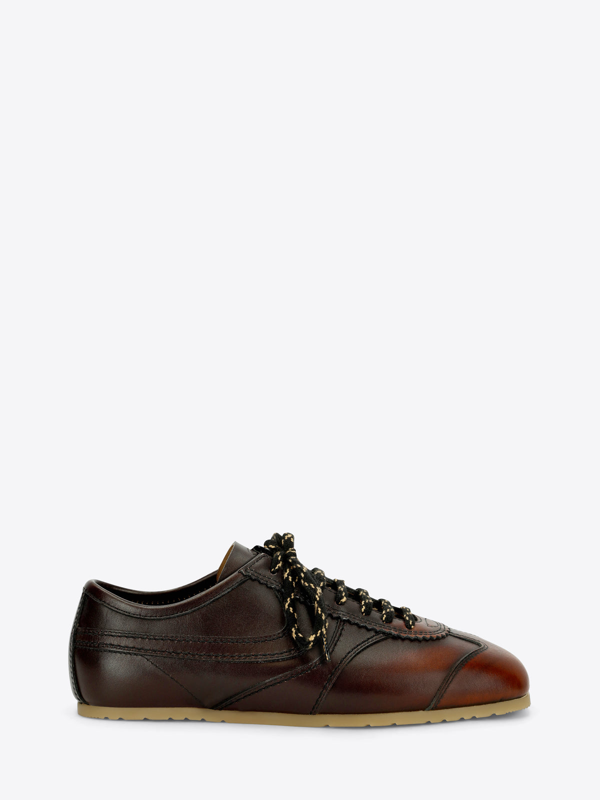 A dark brown leather low-top sneaker with decorative laces, a brown leather toe cap, and a light tan rubber sole, shown against a light gray background.