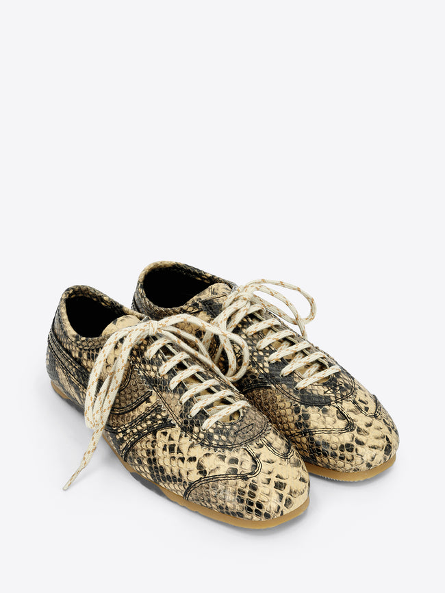 Beige and black snakeskin-effect lace-up sneakers with cream laces and a slim gum sole on a light gray background.