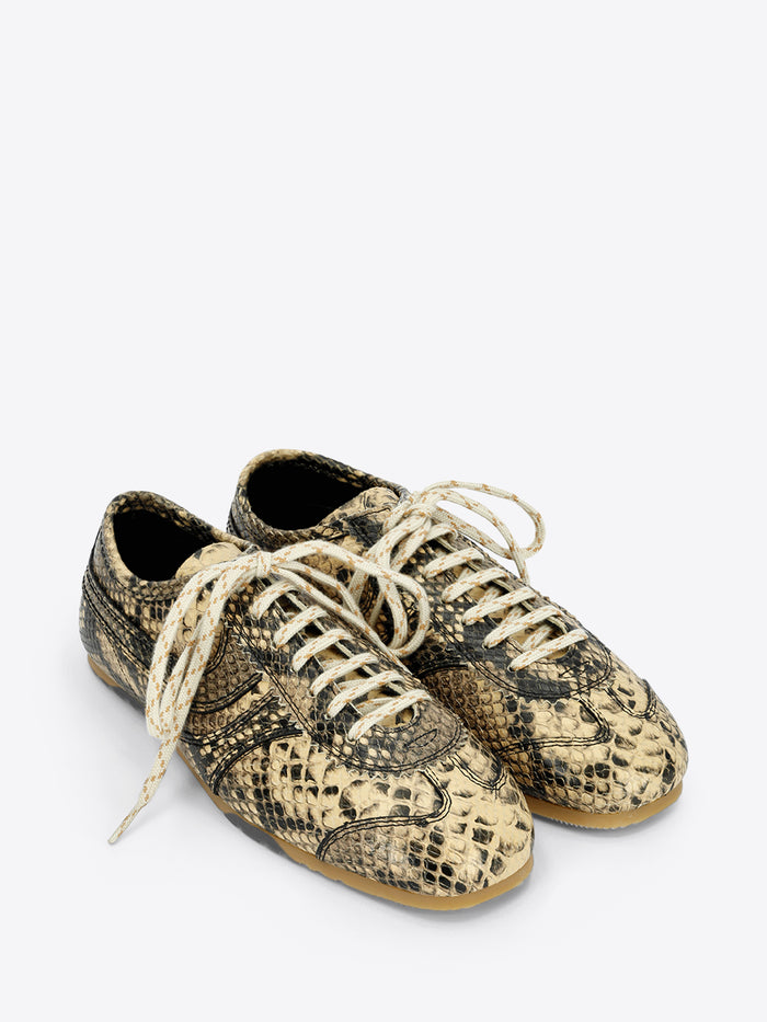 Beige and black snakeskin-effect lace-up sneakers with cream laces and a slim gum sole on a light gray background.