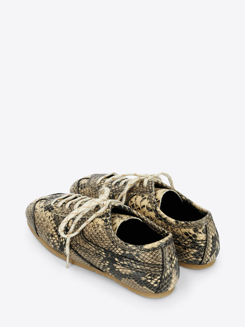 Beige and black snakeskin-effect lace-up sneakers with cream laces and a slim gum sole on a light gray background.