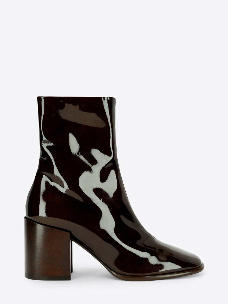 Dark olive patent leather ankle boot with a rounded square toe and chunky block heel on a light gray background.