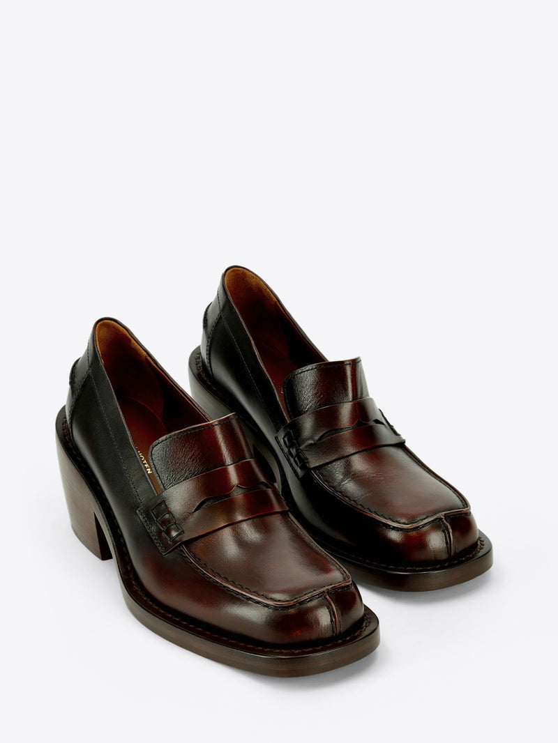 Dark brown leather penny loafer with a raised tongue, square moc toe, and chunky stacked block heel on a light gray background.