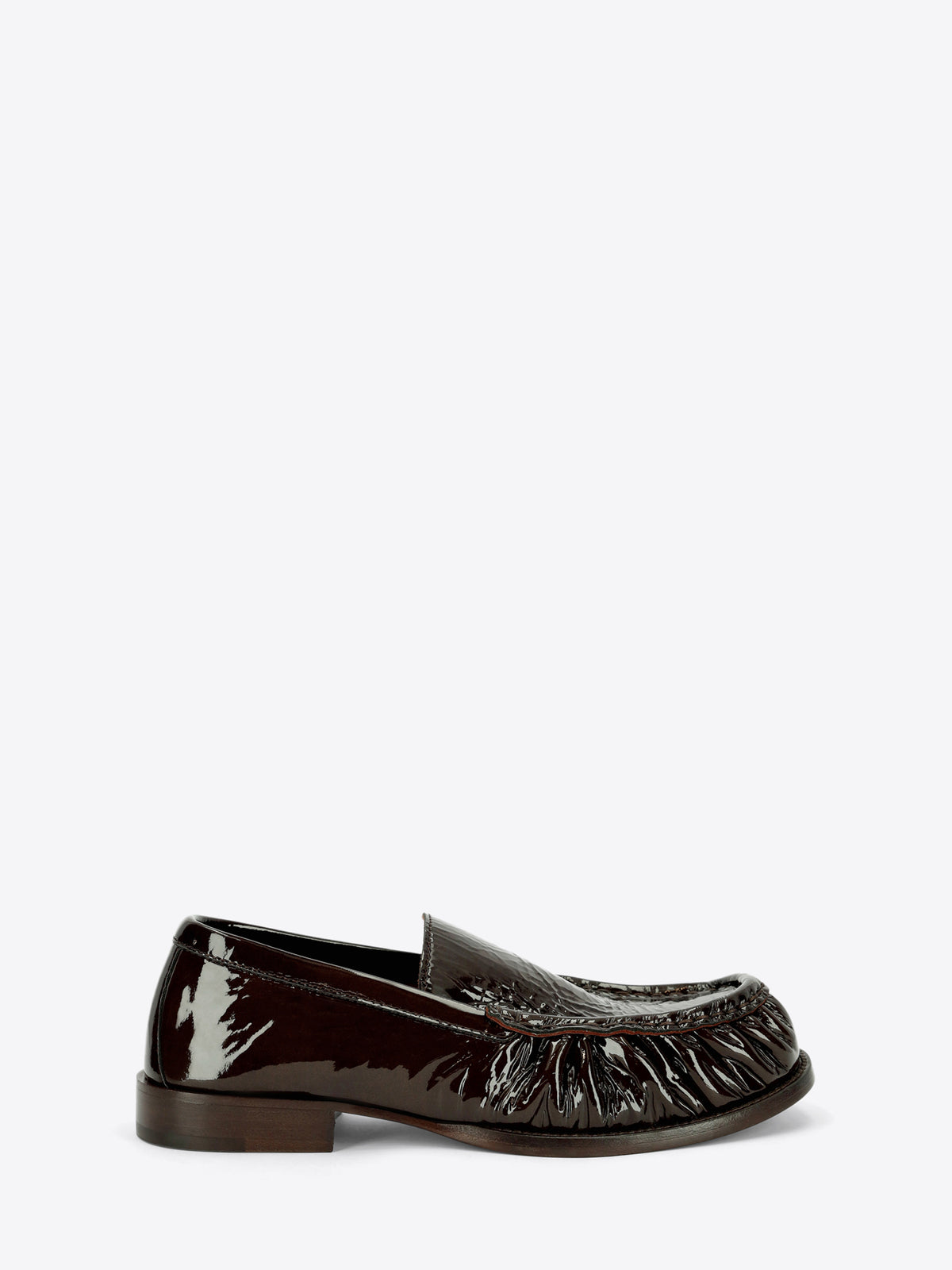 Dark brown patent leather loafer with gathered detailing around the rounded toe and a low stacked heel on a light gray background.