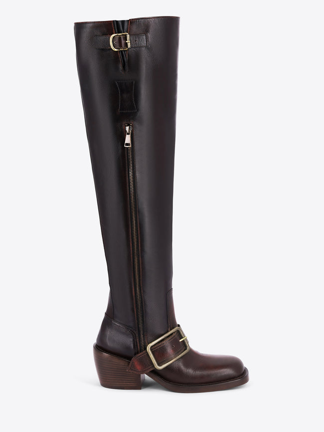 A dark brown leather knee-high boot with a side zipper, a decorative strap with a gold buckle near the top, and a matching buckle on the lower shaft, shown against a light gray background.