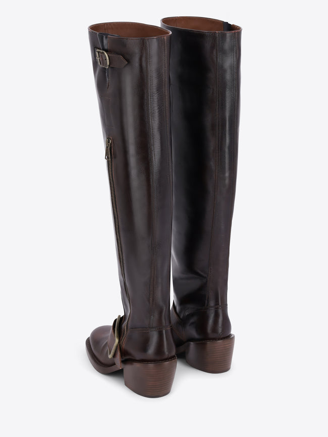 A pair of dark brown leather knee-high boots with a side zipper, a decorative strap with a gold buckle near the top, and a matching buckle on the lower shaft, shown against a light gray background.