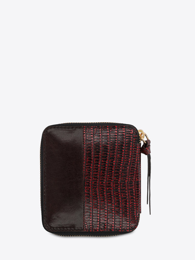 A small zip-around wallet with a split design: one side features a red and black crocodile-embossed texture, and the other side is smooth dark brown on the light gray background. 