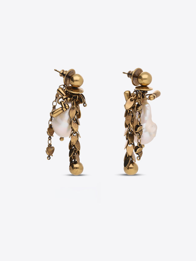 A pair of gold-toned statement dangle earrings featuring irregular white baroque pearls and textured gold leaf-like details, shown against a light gray background.