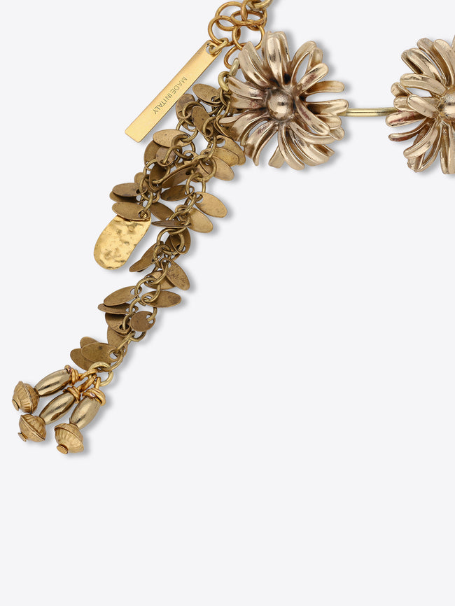 Close-up of an old brass charm bracelet with a sculpted flower, cascading leaf-shaped charms, bud pendants, and a “Made in Italy” tag.