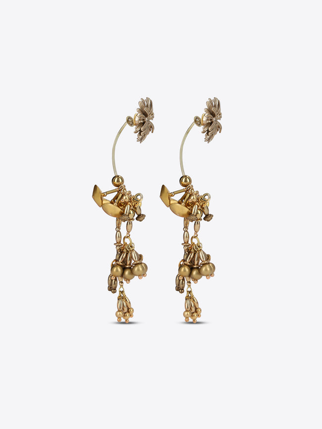 A pair of gold-toned dangle earrings with floral stud tops, small winged fairy motifs, and dangling bead clusters, shown on a light gray background.