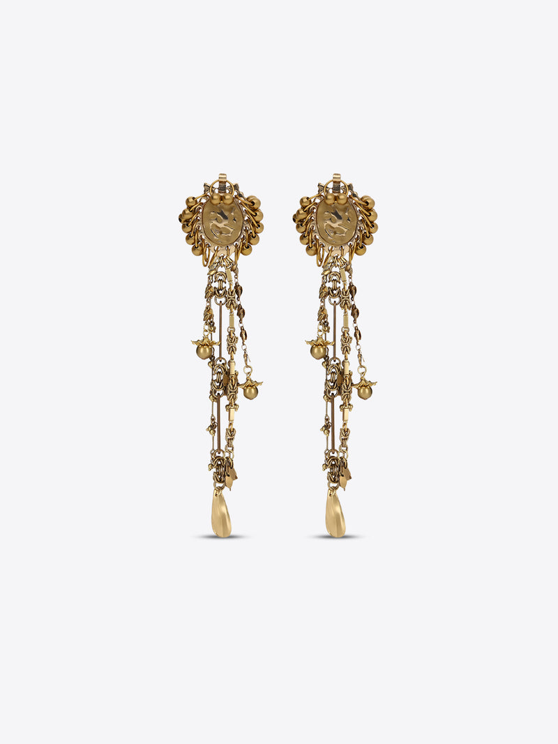 Pair of old brass drop earrings with oval medallions, cascading chains, floral charms, and teardrop pendants on a light gray background.
