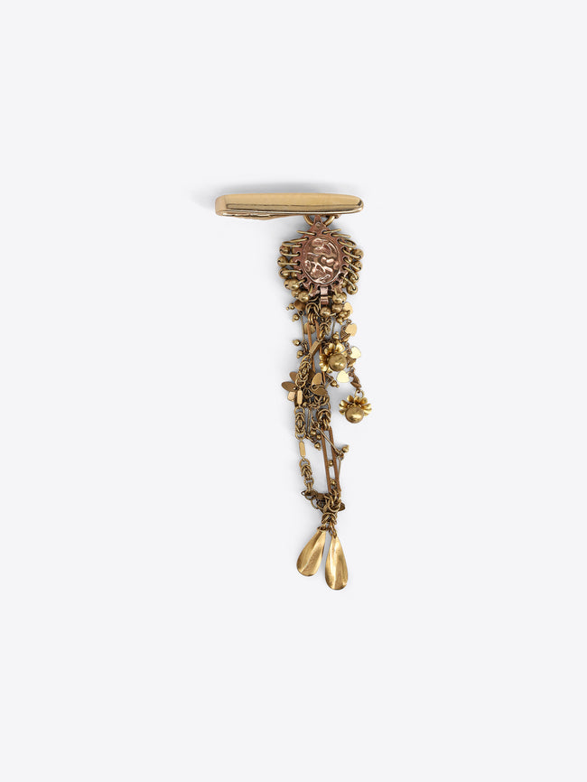 Back view of a gold-toned flower-shaped button cover, showing its fastening mechanism on a light gray background.