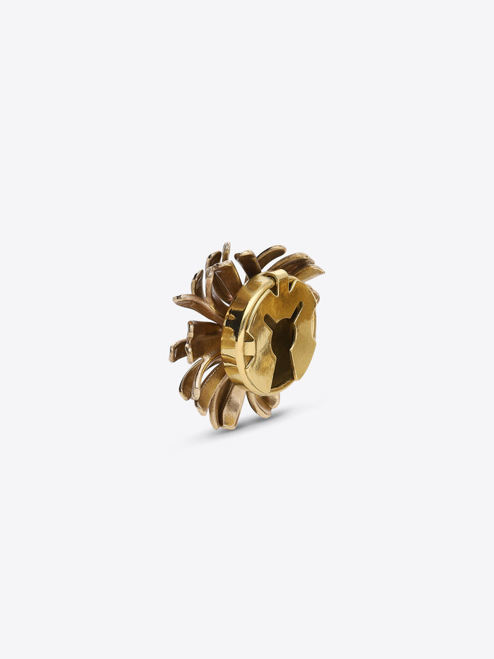 Back view of a gold-toned flower-shaped button cover, showing its fastening mechanism on a light gray background
