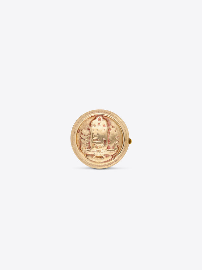 Front view of a round gold-toned button cover with an embossed medallion design on a light gray background.
