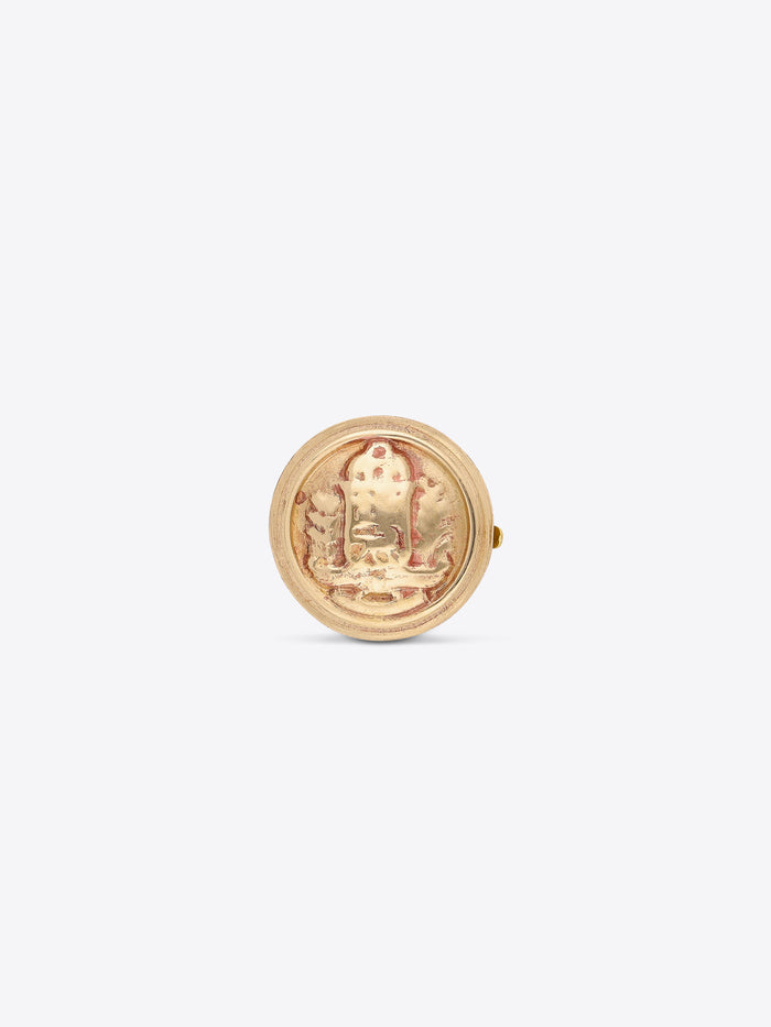 Front view of a round gold-toned button cover with an embossed medallion design on a light gray background.
