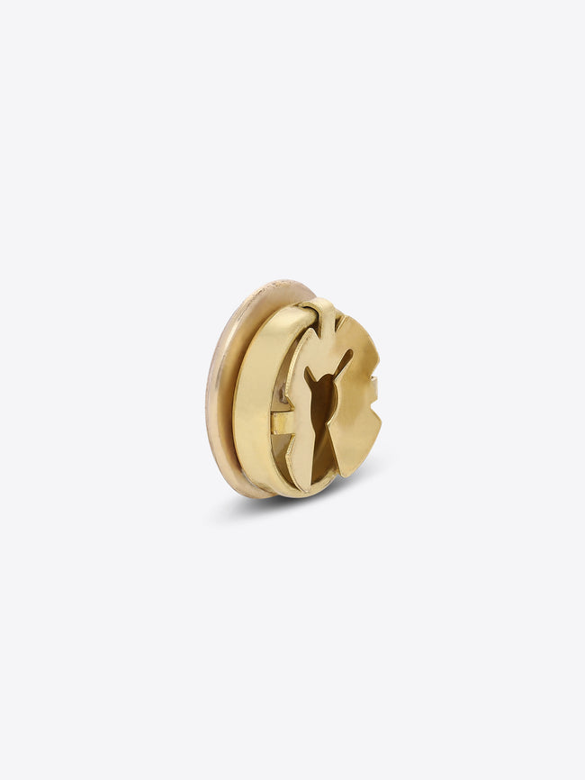 Back view of a round gold-toned button cover, showing its fastening mechanism on a light gray background.
