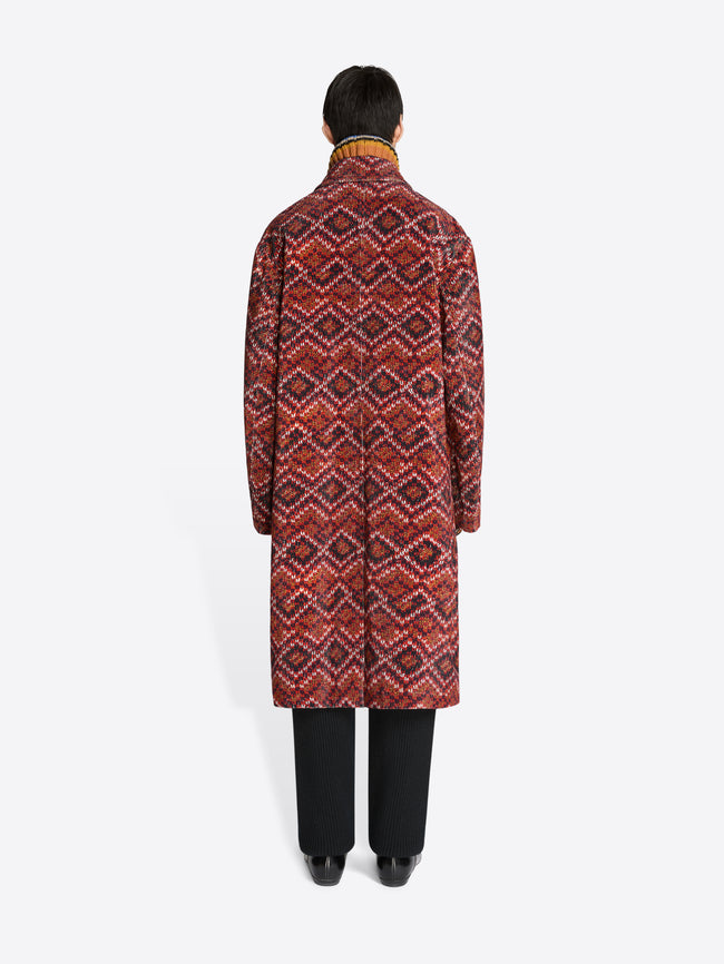 Back view of a person wearing a patterned coat on a white background