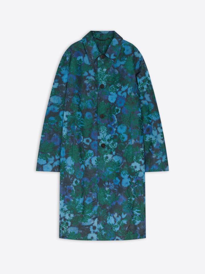 A long-sleeve button-front coat with a pointed collar, featuring an all-over abstract floral pattern in shades of blue, teal, and green, displayed against a light gray background.