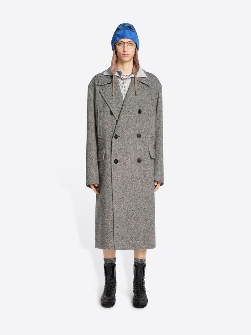 Person wearing a gray coat, blue hat, and black boots on a white background