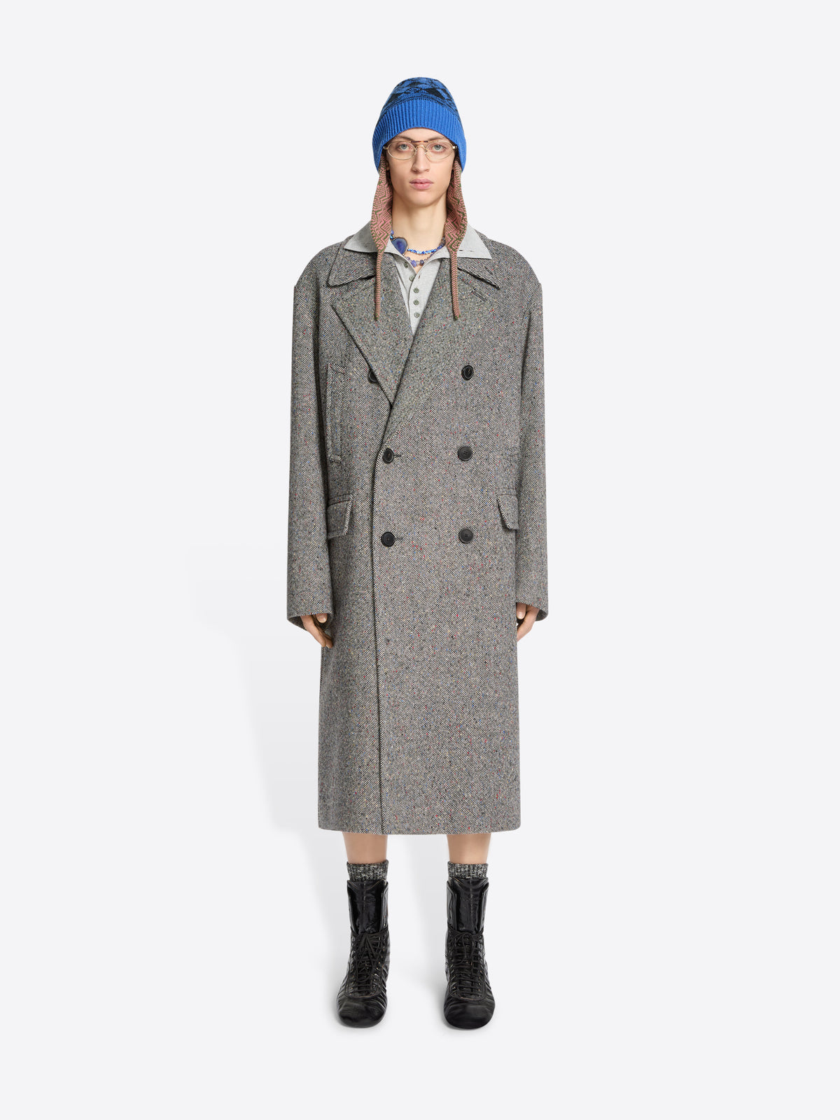 Person wearing a gray coat, blue hat, and black boots on a white background
