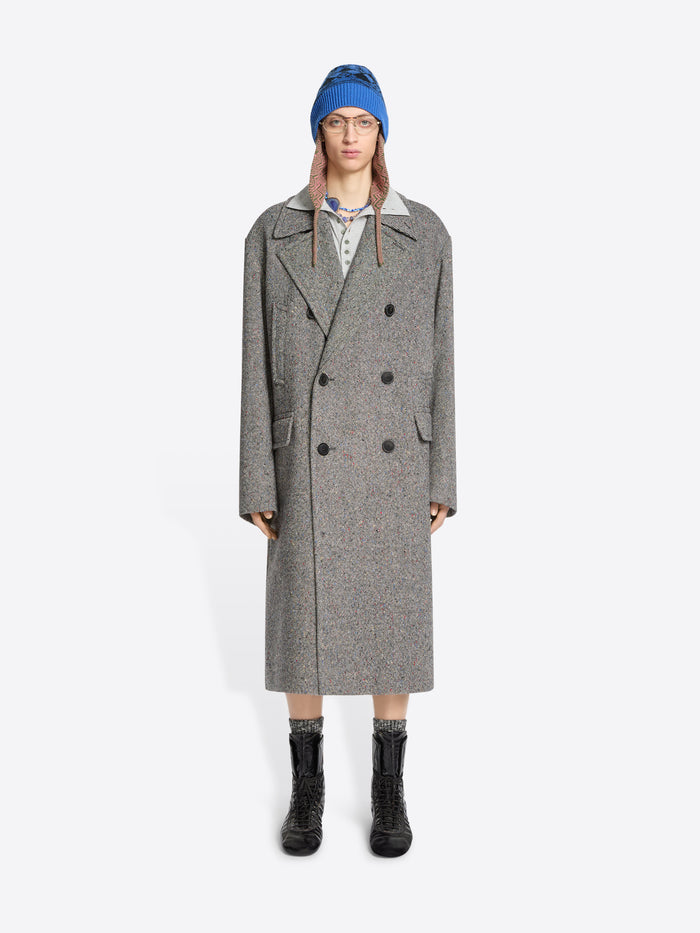 Person wearing a gray coat, blue hat, and black boots on a white background