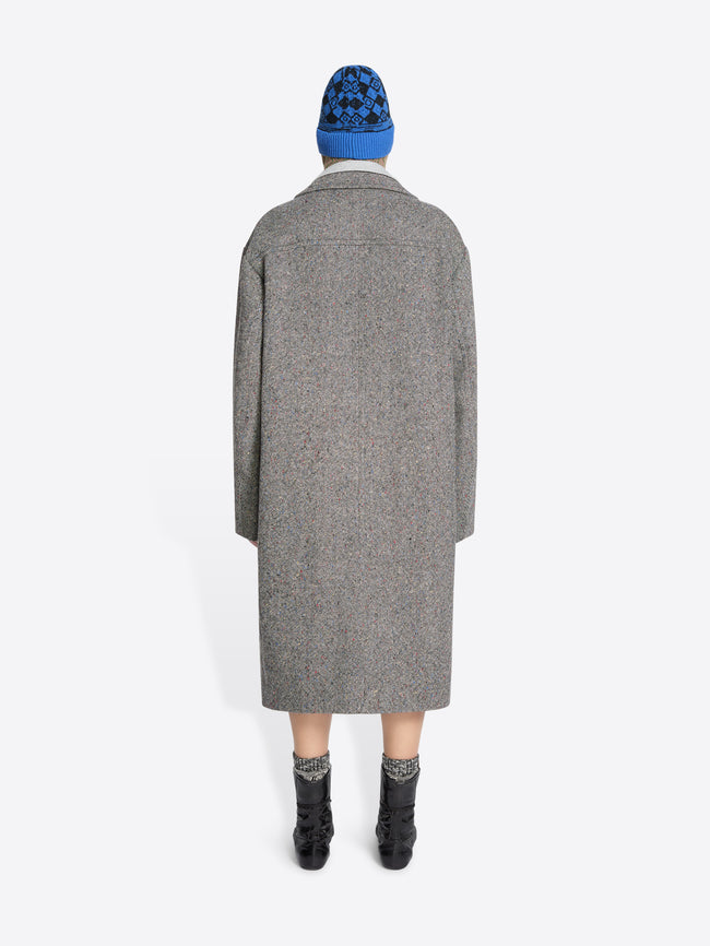 Back view of a person wearing a gray coat and blue beanie on a white background